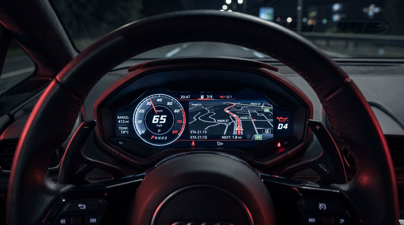 Digital instrument cluster behind a car steering wheel at night